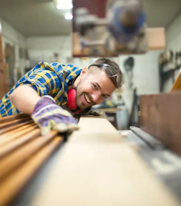 Wood furniture manufacturing process with skilled carpenter shaping custom wooden pieces in woodworking workshop.
