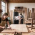 Skilled wood furniture makers crafting custom solid wood furniture in a professional woodworking workshop using traditional hand tools and premium hardwood.