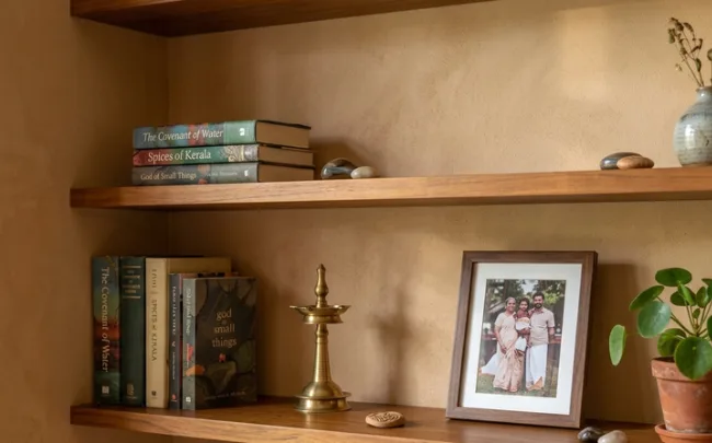 Close-up of wall decor for living room shelves styled with books, a brass lamp and a plant, with space left empty